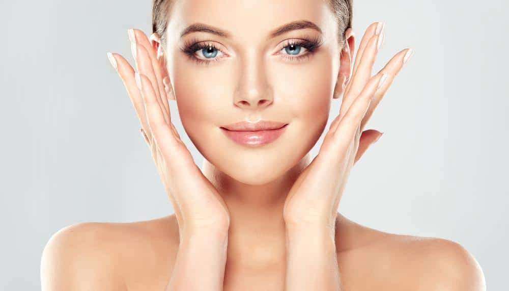 Woman with smooth, natural-looking facial skin gently touching her face