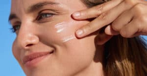 Person applying sunscreen to their cheek outdoors to protect skin from UV exposure and environmental damage in Vancouver.